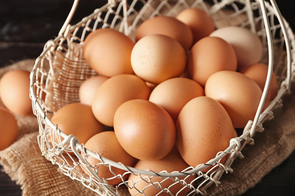 Cesta con huevos de gallina crudos sobre mesa de madera
 - Foto, imagen