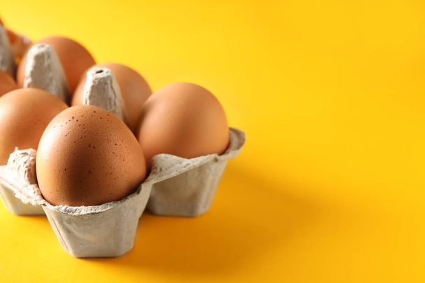 Carton box with raw chicken eggs on color table - Photo, image