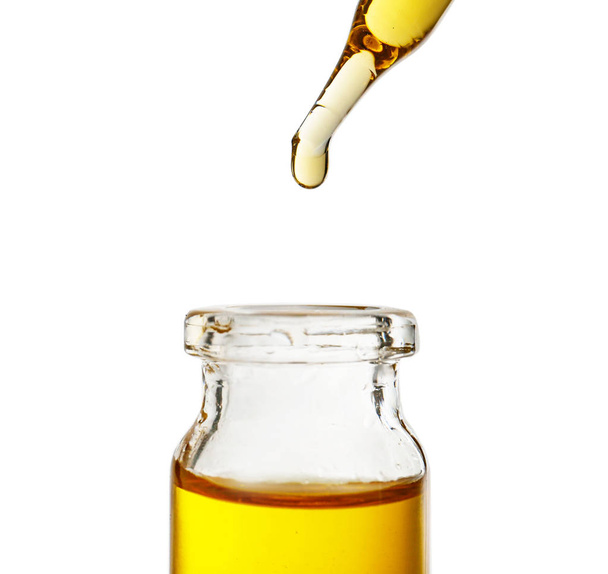 Tropfendes Öl aus der Pipette in Glasflasche auf weißem Hintergrund - Foto, Bild