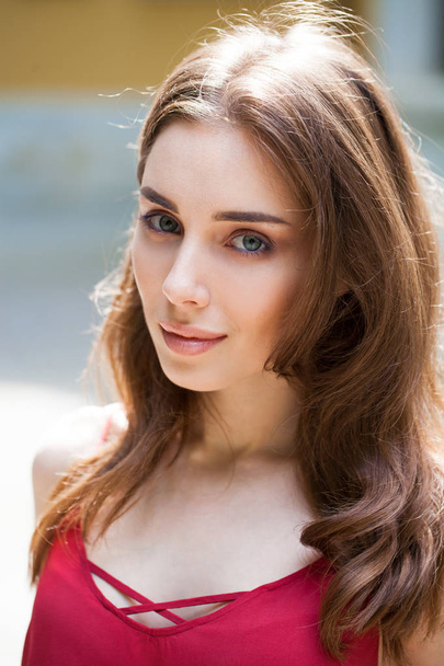 Closeup portrait of a young beautiful brunette woman on summer background - 写真・画像