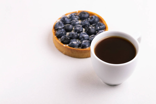 Tasty blueberry tart with vanilla cream and cup of coffee on light marble background. Copy space. Horizontal view - Foto, imagen