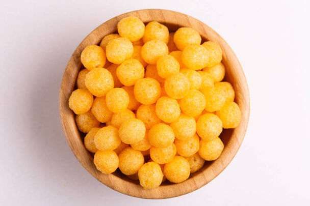 Cheese puff balls in wooden bowl on light background. Cinema snacks. Copy space - Foto, afbeelding