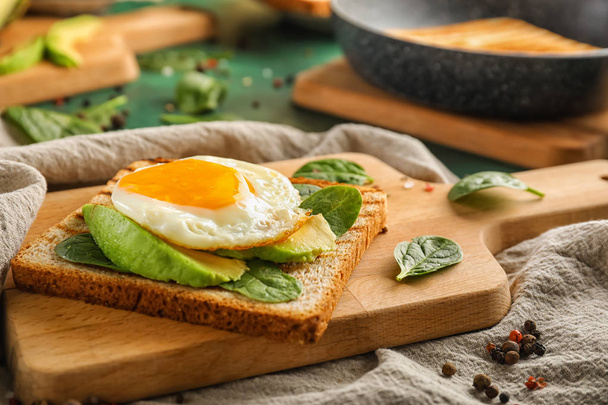 Φρυγανισμένο ψωμί με νόστιμο τηγανητό αυγό σε ξύλινη σανίδα - Φωτογραφία, εικόνα