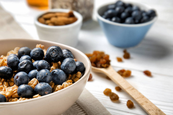 Granola with blueberries in bowl on white table - Fotoğraf, Görsel