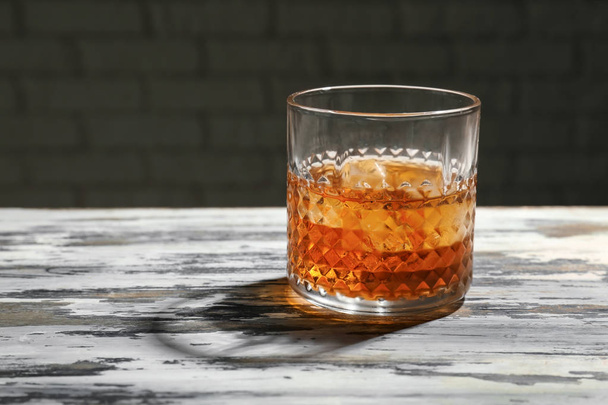 Glass of whiskey on wooden table - Фото, изображение