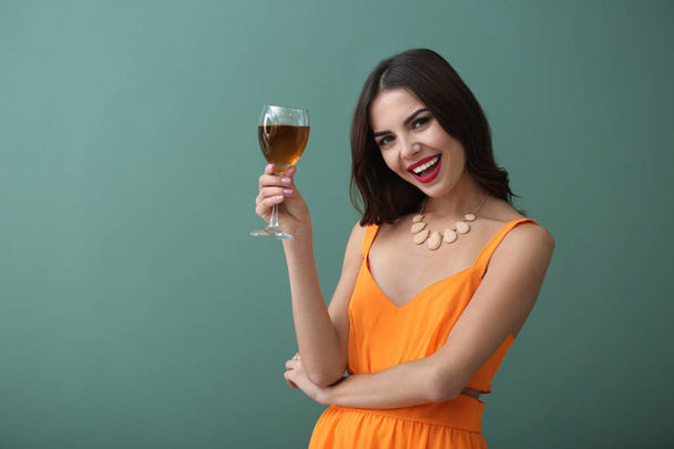 schöne junge Frau mit einem Glas Wein auf farbigem Hintergrund - Foto, Bild