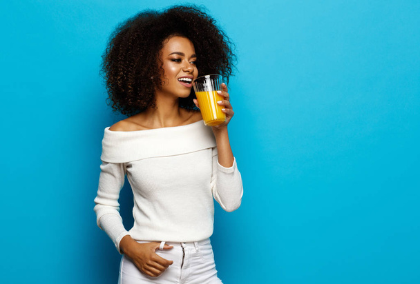 Bella ragazza afroamericana con spazio copia bere un succo d'arancia
 - Foto, immagini