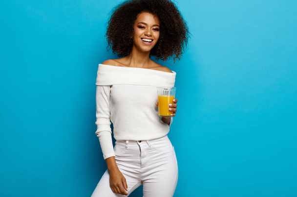 Beautiful smiling african american girl with a glass of orange juice  - 写真・画像