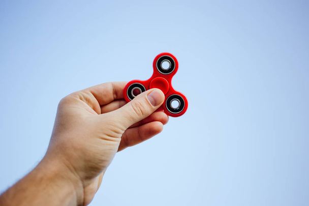 Close up of a man's hand who is holding red fidget spinner. - Foto, Imagen