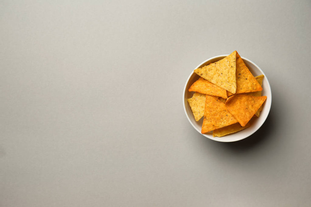 Mísa s chutné kukuřičnými chipsy na šedém pozadí - Fotografie, Obrázek
