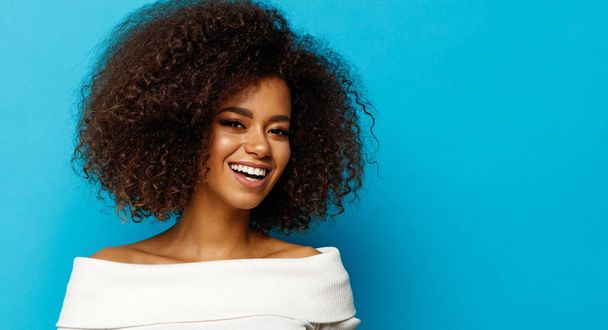 Beautiful black woman with white teeth smiling isolated on blue background - Fotó, kép