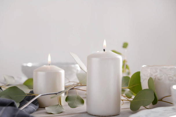 brennende Kerzen mit Eukalyptuszweigen auf Holztisch - Foto, Bild