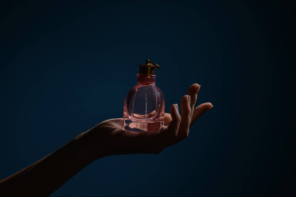Woman holding bottle of perfume on dark color background - Fotografie, Obrázek