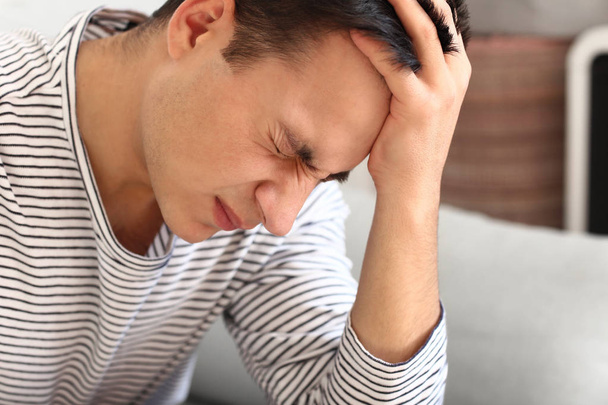 молодий чоловік, що страждає від головного болю вдома
 - Фото, зображення