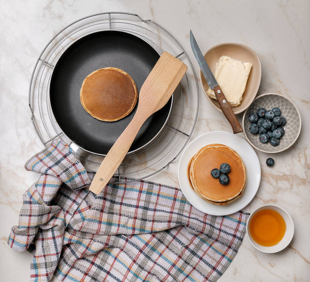 Panqueques calientes y sabrosos con arándanos, miel y mantequilla en una mesa ligera
 - Foto, imagen