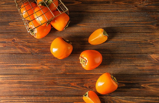 Ripe persimmons on wooden background, top view - Photo, Image