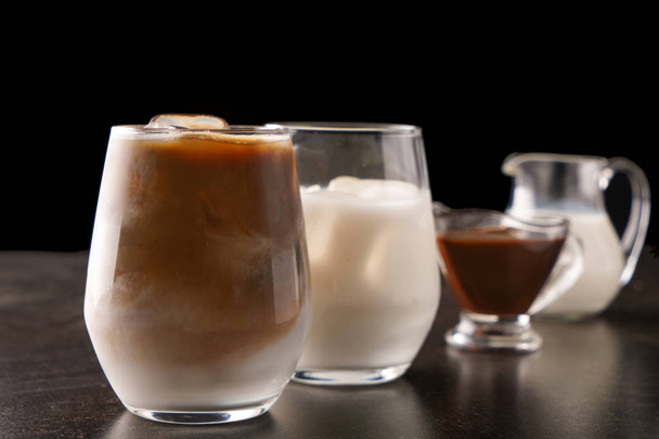 Glass of tasty cold coffee and ingredients on dark table - Фото, зображення