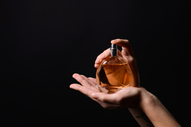 Woman with bottle of perfume on dark background - Valokuva, kuva