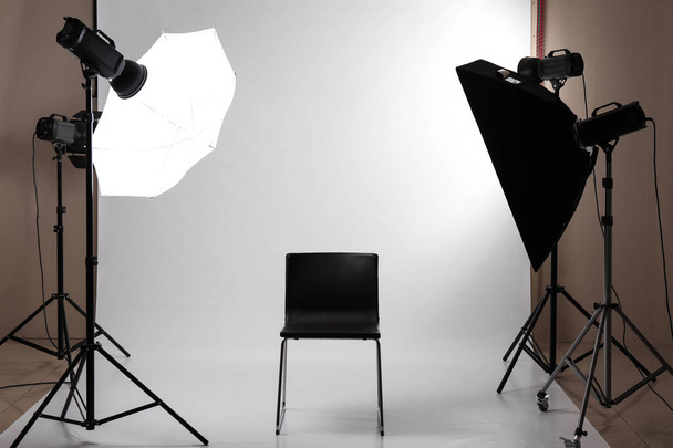 Интерьер современной фотостудии с профессиональным оборудованием и стулом
 - Фото, изображение
