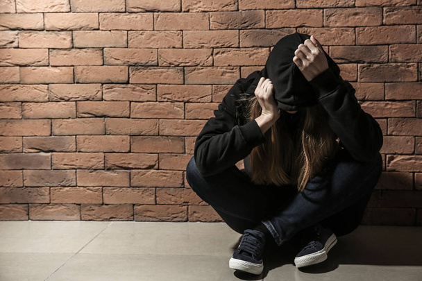Una drogadicta deprimida cerca de la pared de ladrillo. Concepto de adicción
 - Foto, imagen
