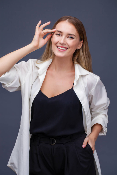 glückliches blondes Model. Porträt einer schönen jungen Frau in weißem Hemd, isoliert auf grauem Hintergrund - Foto, Bild