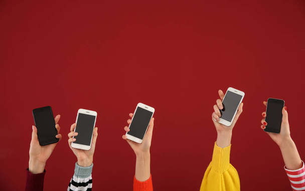 Young people holding mobile phones on color background. Concept of addiction - Фото, изображение