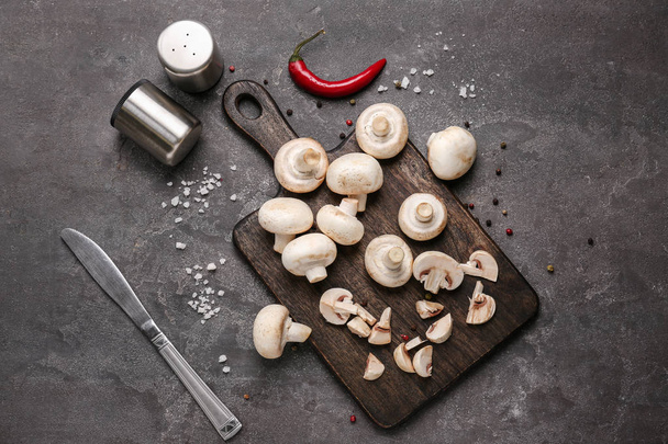 Dřevěná deska s čerstvými houbami a koření na šedý stůl - Fotografie, Obrázek