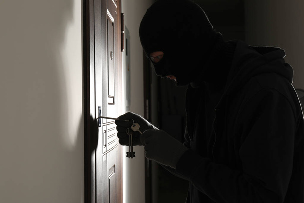 Mężczyzna złodziej otwierania drzwi z kluczami w pomieszczeniu - Zdjęcie, obraz