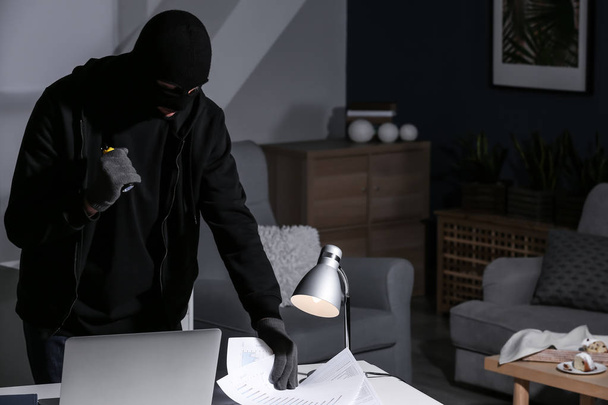 Αρσενικό κλέφτης με το φακό ψάχνει για έγγραφα σε εσωτερικούς χώρους - Φωτογραφία, εικόνα