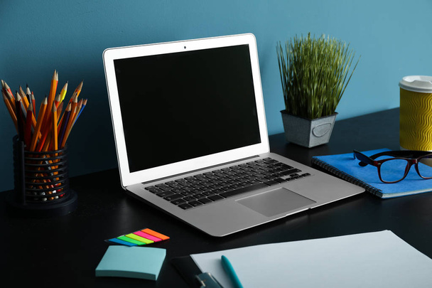 Stylowe miejsce pracy z nowoczesnym laptopem w pobliżu ściany koloru - Zdjęcie, obraz