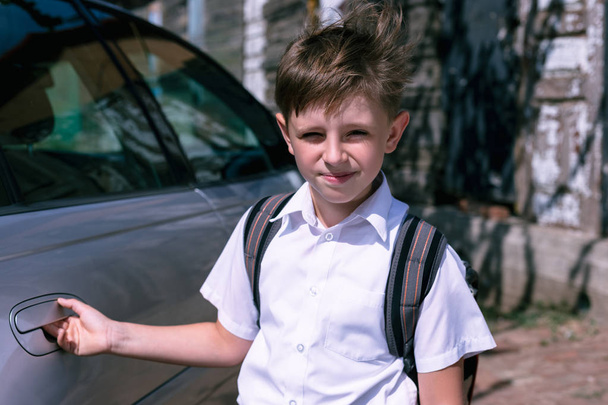 Az általános iskola fiú egy hátizsák, közvetlenül az autó az utcán. Vissza a concept iskolai. - Fotó, kép