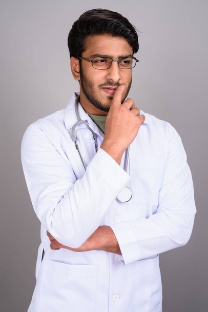Портрет индийского врача, думающего на сером фоне
 - Фото, изображение