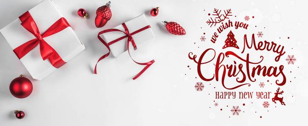 Hyvää joulua Typografinen valkoisella taustalla lahjapakkauksia ja punainen koristelu. Joulun ja uudenvuoden kortti. Tasainen, ylhäältä
 - Valokuva, kuva