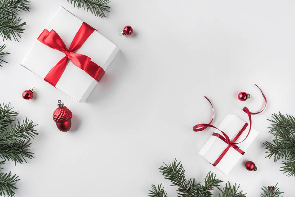 Cajas de regalo de Navidad sobre fondo blanco con ramas de abeto, conos de pino, cinta roja. Tema Navidad y Feliz Año Nuevo. Piso tendido, vista superior
 - Foto, Imagen
