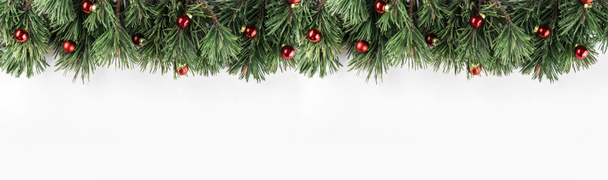 Guirlande de Noël de branches de sapin avec décoration rouge sur fond blanc. Thème Noël et Bonne Année. Couchage plat, vue sur le dessus, large composition
 - Photo, image