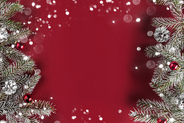 Estrutura de layout criativo feito de ramos de abeto de Natal, cones de pinho, presentes, decoração vermelha no fundo vermelho. Natal e tema de Ano Novo, bokeh, brilhando. Deitado plano, vista superior
 - Foto, Imagem
