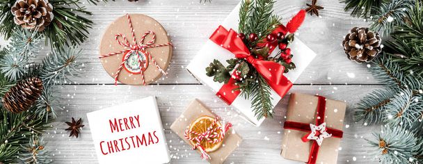 Рождественские подарочные коробки на белом деревянном фоне с еловыми ветвями, сосновыми шишками. Новогодняя тема, снежинки. Плоский, вид сверху
 - Фото, изображение