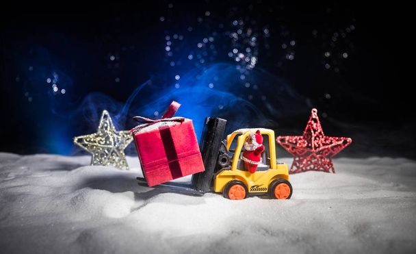 Caja de regalo miniatura por la máquina de la carretilla elevadora en la nieve, imagen determinada para las vacaciones de Navidad y el concepto feliz de la celebración del regalo del año nuevo. Enfoque selectivo
 - Foto, Imagen