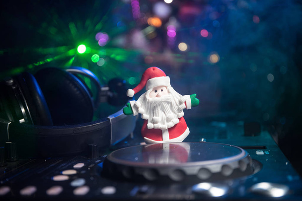 Dj Mixer with headphones on dark nightclub background with Christmas tree New Year Eve. Закройте вид на новогодние элементы на диджейском столе. Концепция праздничной вечеринки. Пустое пространство
 - Фото, изображение