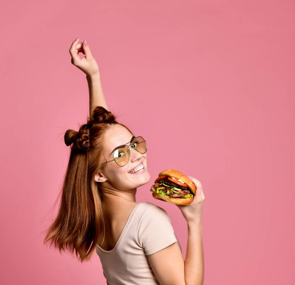 Horizontal studio shot of pretty young woman holding a burger - Фото, зображення