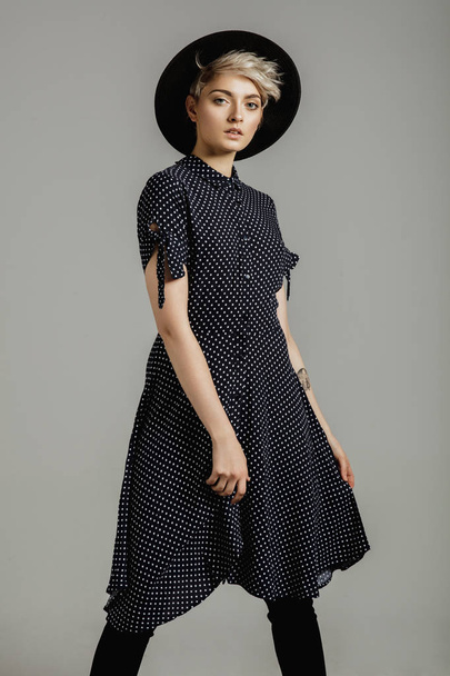 Fashion portrait of female model with blond short hair wear black hat and fashionable dress - 写真・画像