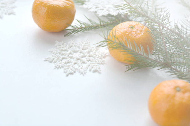 A branch of a Christmas tree, snowflakes, Christmas toys and tangerines on a white background. - Photo, image