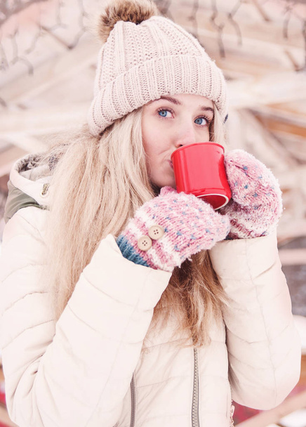美しい若い女性の笑みを浮かべて屋外熱いココアを飲みます。雪の天気。冬の休日. - 写真・画像