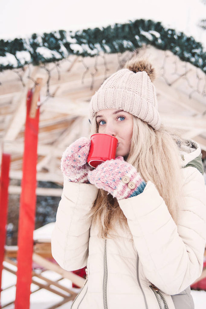 Усміхаючись красива молода жінка п'є гаряче какао на відкритому повітрі. Сніжна погода. Зимові свята
. - Фото, зображення