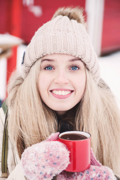 Uśmiechający się piękna młoda kobieta napoje gorące kakao odkryty. Snowy pogody. Ferie zimowe. - Zdjęcie, obraz
