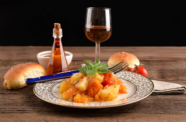 Золотое блюдо из тыквы и картошки с бокалом вина на деревянном столе
 - Фото, изображение