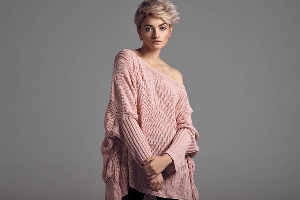 Fashion portrait of female model with blond short hair wear sweater  - Фото, изображение