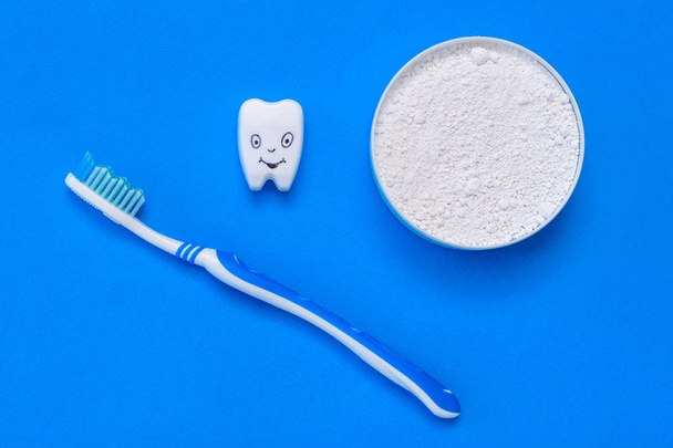 De tand beeldje glimlach naast de tand poeder en tandenborstel. Mondverzorging producten. Het uitzicht vanaf de top. Plat leggen. - Foto, afbeelding