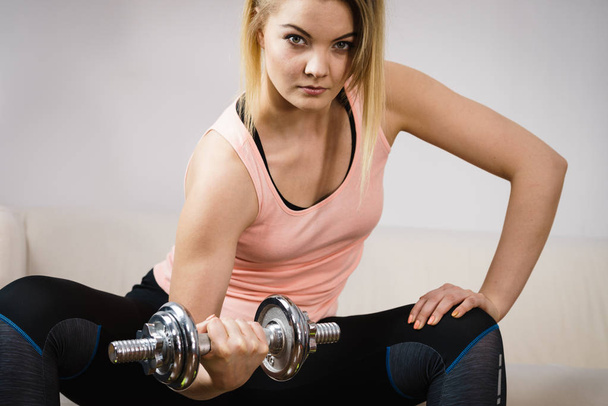 Young woman working out at home with heavy dumbbells. Training at home, being fit and healthy. - Foto, afbeelding