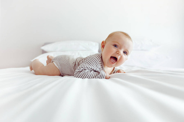 Charming happy baby on white bed - Foto, Imagen
